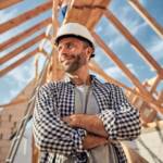 Pleased man in a hard hat posing under a wooden roof
